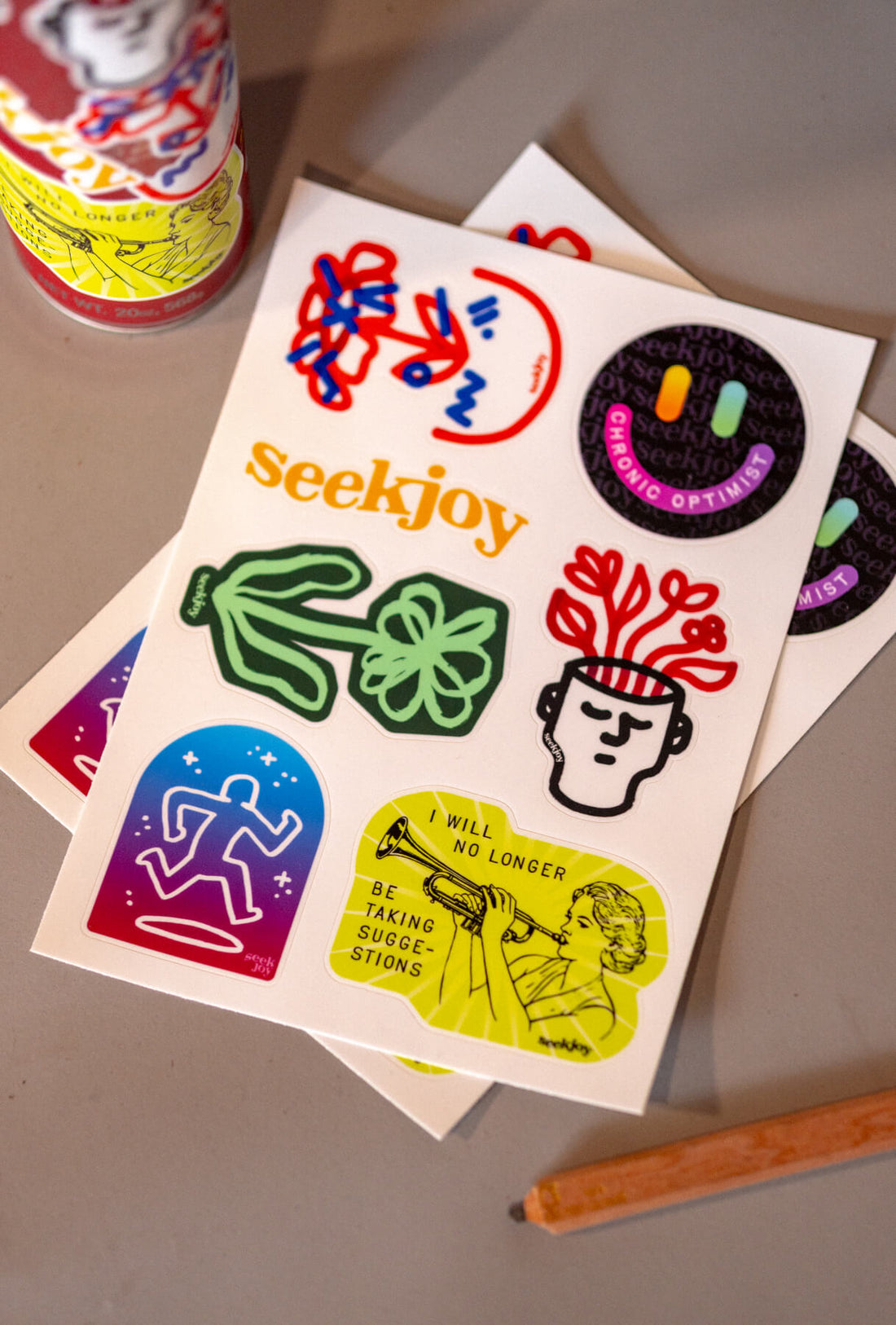 The seekjoy sticker sheet laid out beside a sticker-covered spray can