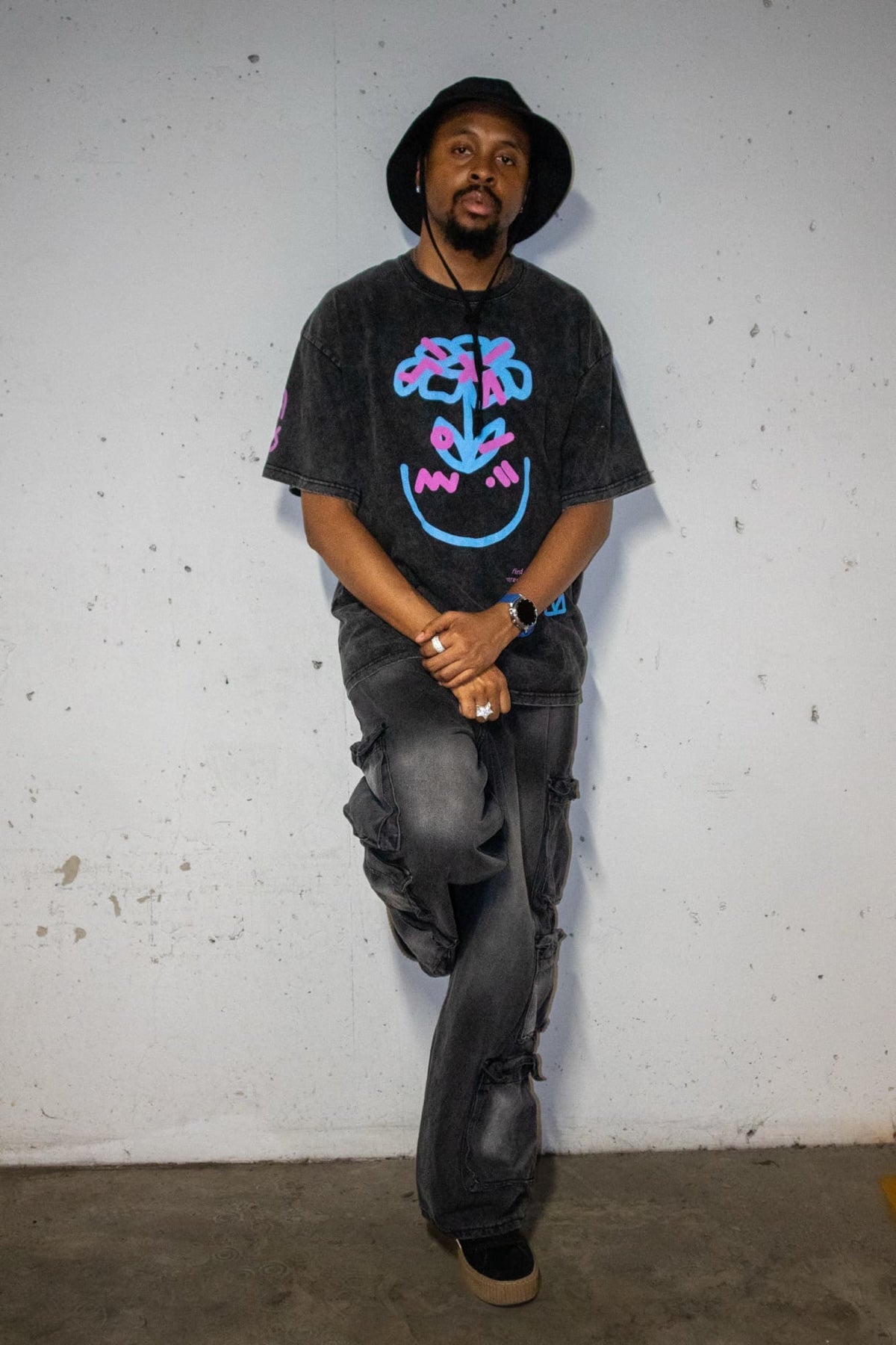 Model standing against a white wall wearing the Perception tee, full length